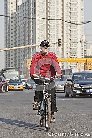 Young man cycles in Beijing center with apartment buildings on bakcground, China Editorial Stock Photo